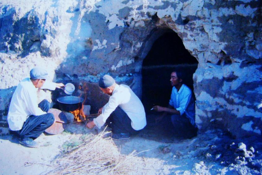 1983年，“六老漢”一代治沙人在“地窩子”生活做飯,。新華社發(fā)（八步沙林場(chǎng)供圖）